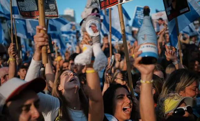 People react as they gather to watch a live broadcast of Israeli hostages released from Gaza at a plaza known as hostages square in Tel Aviv, Israel, Monday, Oct. 13, 2025. The release took place as part of a cease-fire agreement between Israel and Hamas. (AP Photo/Emilio Morenatti)