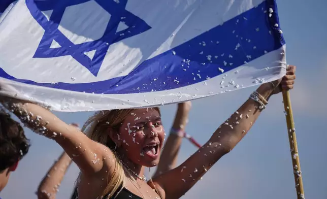 People hold Israeli flag and spray foam in celebration after the arrival of freed hostages at Beilinson Hospital in Petah Tikva, Israel, following their release from Hamas captivity in the Gaza Strip, Monday, Oct. 13, 2025. (AP Photo/Ariel Schalit)