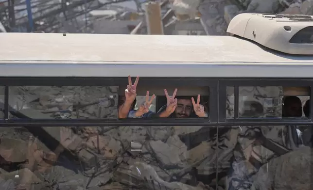 Freed Palestinian prisoners on a bus flash the victory sign as they pass destroyed buildings in the Gaza Strip after their release from Israeli jails under a ceasefire agreement between Hamas and Israel, in Khan Younis, southern Gaza Strip, Monday, Oct. 13, 2025. (AP Photo/Jehad Alshrafi)