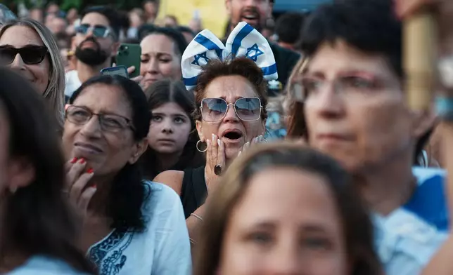 People react as they gather to watch a live broadcast of Israeli hostages released from Gaza at a plaza known as hostages square in Tel Aviv, Israel, Monday, Oct. 13, 2025. The release took place as part of a cease-fire agreement between Israel and Hamas. (AP Photo/Emilio Morenatti)