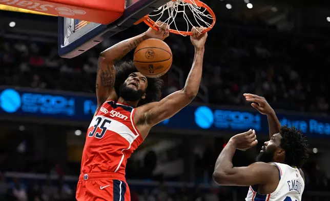Washington Wizards forward Marvin Bagley III (35) dunks against Philadelphia 76ers center Joel Embiid during the first half of an NBA basketball game Tuesday, Oct. 28, 2025, in Washington. (AP Photo/John McDonnell)