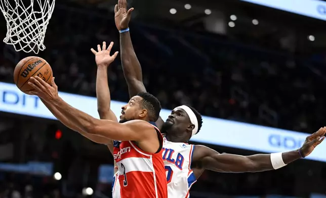 Washington Wizards guard CJ McCollum, left, rises past Philadelphia 76ers center Adem Bona for a basket during the first half of an NBA basketball game Tuesday, Oct. 28, 2025, in Washington. (AP Photo/John McDonnell)