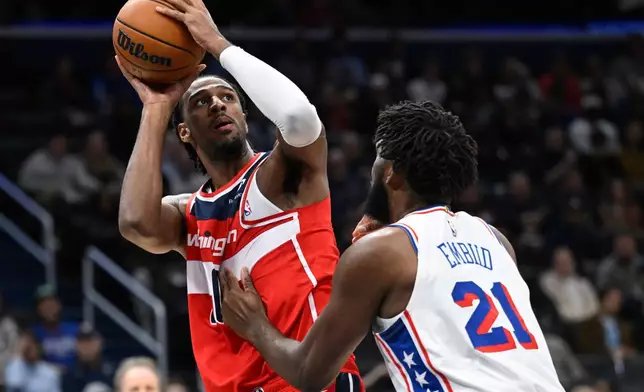 Washington Wizards center Alex Sarr shoots a basket over Philadelphia 76ers center Joel Embiid (21)during the first half of an NBA basketball game Tuesday, Oct. 28, 2025, in Washington. (AP Photo/John McDonnell)