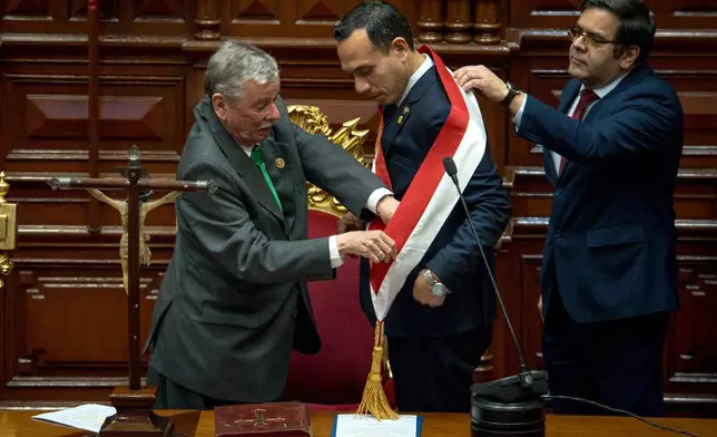 Peru's former president of the Congress Jose Jeri, center, receives the presidential sash from congressman Fernando Rospigliosi, left, as he is sworn-in as the interim president in Lima, Peru, Friday, Oct. 10, 2025. (AP Photo/John Reyes)