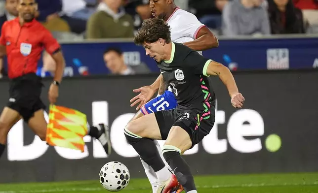 Australia defender Jordan Bos, front, fights for control of the ball with United States defender Alex Freeman in the first half of an international friendly soccer match Tuesday, Oct. 14, 2025, in Commerce City, Colo. (AP Photo/David Zalubowski)