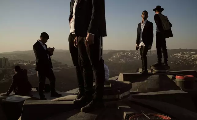 Ultra-Orthodox Jewish men stand of a roof during a rally against plans to force them to serve in the Israeli military, in Jerusalem, Thursday, Oct. 30, 2025. (AP Photo/Leo Correa)