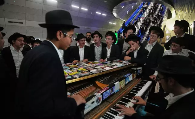 Ultra-Orthodox Jewish men play music before boarding a train following a rally protesting plans to require them to serve in the Israeli military, in Jerusalem, Thursday, Oct. 30, 2025. (AP Photo/Ohad Zwigenberg)