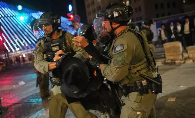 Israeli police officers disperse ultra-Orthodox Jewish men blocking a road during a protest against plans to require them to serve in the Israeli military, in Jerusalem, Thursday, Oct. 30, 2025. (AP Photo/Ohad Zwigenberg)