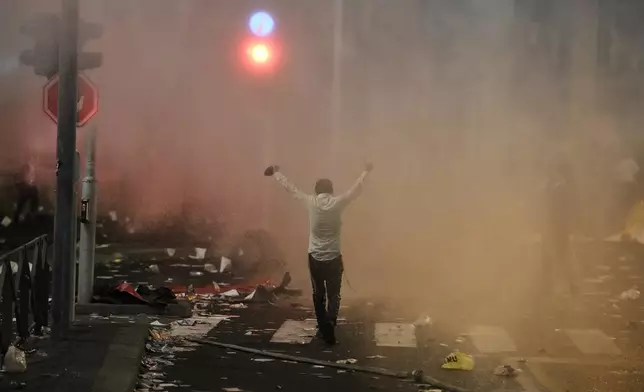 An ultra-Orthodox Jewish man stands in front of a police water cannon during a protest against plans to require ultra-Orthodox men to serve in the Israeli military, in Jerusalem, Thursday, Oct. 30, 2025. (AP Photo/Leo Correa)