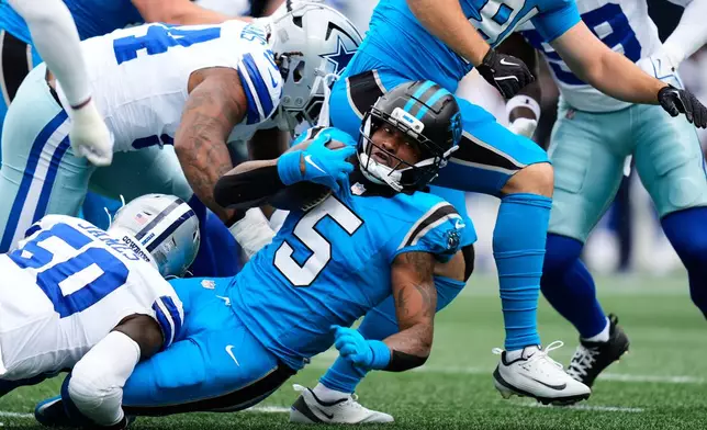 Carolina Panthers running back Rico Dowdle (5) is stopped as he runs the ball by Dallas Cowboys linebacker Shemar James (50) in the first half of an NFL football game, Sunday, Oct. 12, 2025, in Charlotte, N.C. (AP Photo/Erik Verduzco)