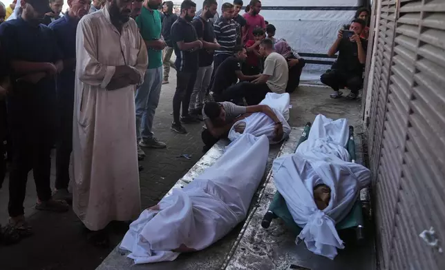 Mourners pray over the bodies of Palestinians killed by Israeli army shelling, during their funeral outside Al-Aqsa Hospital in Deir al-Balah, central Gaza Strip, Saturday, Oct. 4, 2025. (AP Photo/Abdel Kareem Hana)