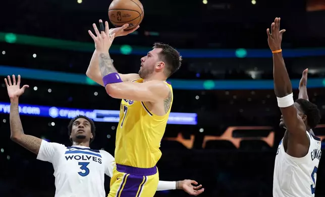 Los Angeles Lakers guard Luka Doncic, center, shoots against Minnesota Timberwolves forward Jaden McDaniels (3) as guard Anthony Edwards, right, watches during the first half of an NBA basketball game, Friday, Oct. 24, 2025, in Los Angeles. (AP Photo/Jessie Alcheh)