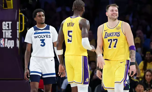 Los Angeles Lakers guard Luka Doncic (77) reacts after scoring a basket as center Deandre Ayton (5) and Minnesota Timberwolves forward Jaden McDaniels (3) look on during the second half of an NBA basketball game, Friday, Oct. 24, 2025, in Los Angeles. (AP Photo/Jessie Alcheh)