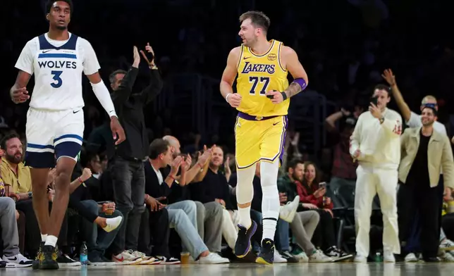 Los Angeles Lakers guard Luka Doncic (77) reacts after making a 3 point basket as Minnesota Timberwolves forward Jaden McDaniels (3) looks on during the second half of an NBA basketball game, Friday, Oct. 24, 2025, in Los Angeles. (AP Photo/Jessie Alcheh)