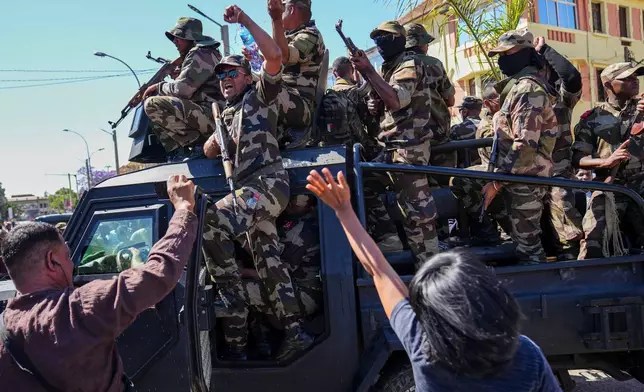 Soldiers are greeted by people gathering for a ceremony in tribute to demonstrators killed during recent anti-government protest in Antananarivo, Madagascar, Sunday, Oct. 12, 2025. (AP Photo/Mamyrael)