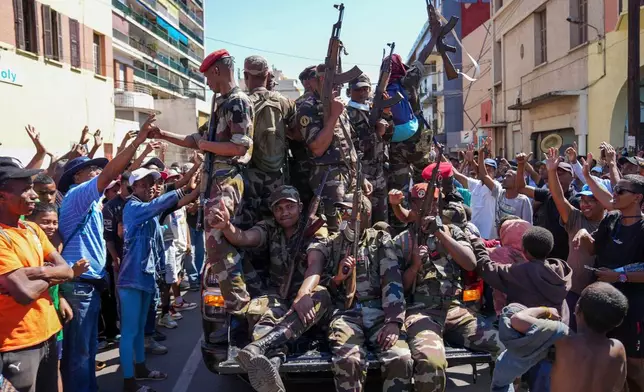 Soldiers are greeted by people gathering for a ceremony in tribute to demonstrators killed during recent anti-government protest in Antananarivo, Madagascar, Sunday, Oct. 12, 2025. (AP Photo/Mamyrael)