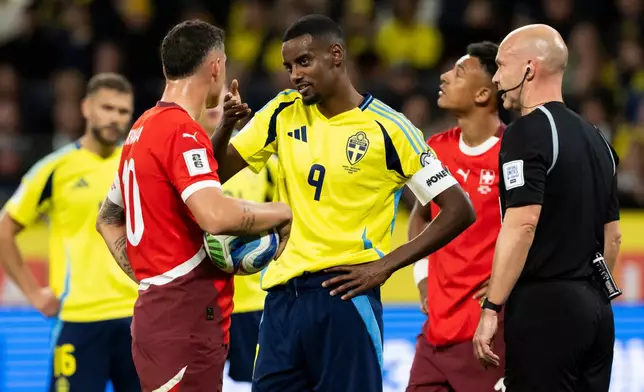 Swedens Alexander Isak, center, talks to Switzerland's Granit Xhaka before the penalty shot during a World Cup qualifying soccer match between Sweden and Switzerland at Strawberry Arena, in Stockholm, Sweden, Friday, Oct. 10, 2025. (Anthony Anex/Keystone via AP)