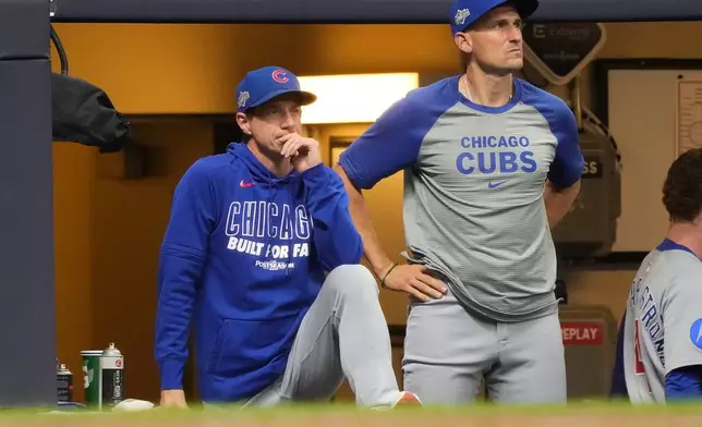 Chicago Cubs manager Craig Counsell, left, and bench coach Ryan Flaherty, right, look on from the dugout during the seventh inning of Game 5 of baseball's National League Division Series against the Milwaukee Brewers, Saturday, Oct. 11, 2025, in Milwaukee. (AP Photo/Kayla Wolf)