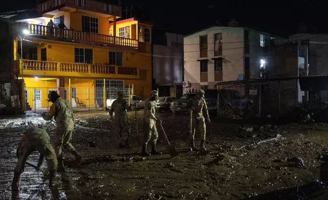 Soldiers clean a flooded street in Poza Rica, Veracruz state, Mexico, Tuesday, Oct. 14, 2025, after torrential rain. (AP Photo/Felix Marquez)