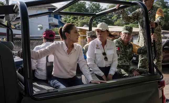 President Claudia Sheinbaum, left, and Veracruz Gov. Rocío Nahle García survey authorities' aid distribution in Poza Rica, Mexico, Sunday, Oct. 12, 2025, after widespread flooding and landslides. (AP Photo/Felix Marquez)