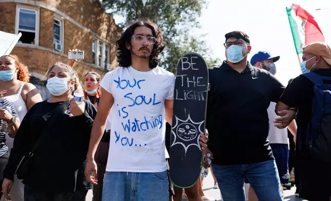 Protesters stand and chant in the Brighton Park neighborhood of Chicago, on Saturday, Oct. 4, 2025, after protesters learned that U.S. Border Patrol shot a woman Saturday morning on Chicago's Southwest Side. (Anthony Vazquez/Chicago Sun-Times via AP)