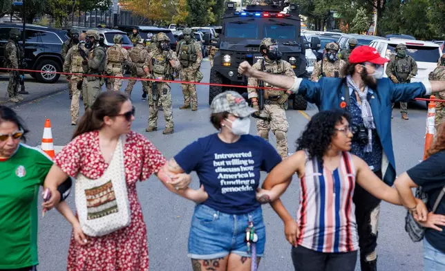 Protestors create a line to maintain distance between ICE officers and protestors in the Brighton Park neighborhood of Chicago, on Saturday, Oct. 4, 2025, after protesters learned that U.S. Border Patrol shot a woman Saturday morning on Chicago's Southwest Side. (Anthony Vazquez/Chicago Sun-Times via AP)