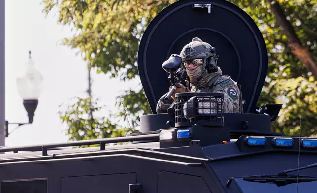 A federal officer stands guard in the Brighton Park neighborhood of Chicago, on Saturday, Oct. 4, 2025, after protesters learned that U.S. Border Patrol shot a woman Saturday morning on Chicago's Southwest Side. (Anthony Vazquez/Chicago Sun-Times via AP)