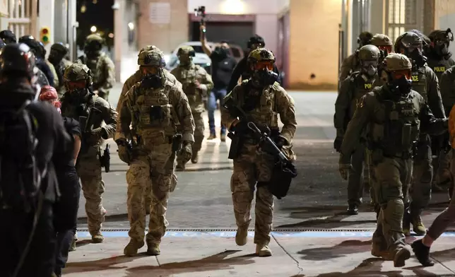 Federal agents walk into the street as people protest outside a U.S. Immigration and Customs Enforcement facility in Portland, Oregon, Friday, Oct. 3, 2025. (AP Photo/Amanda Loman)