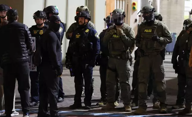 Federal agents line a driveway as people protest outside a U.S. Immigration and Customs Enforcement facility in Portland, Oregon, Friday, Oct. 3, 2025. (AP Photo/Amanda Loman)
