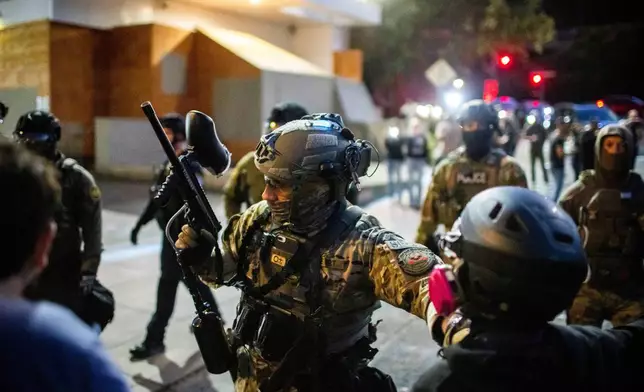 Police and Federal officers stand guard an area by the U.S. Immigration and Customs Enforcement facility in Portland, Ore. on Sunday, October. 5, 2025. (AP Photo/Ethan Swope)