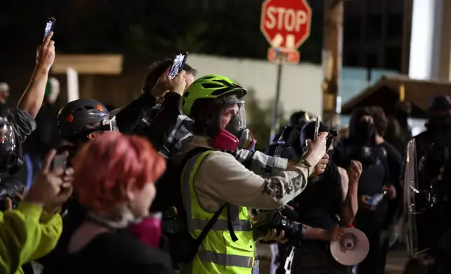 People film as federal agents walk into the street during a protest outside a U.S. Immigration and Customs Enforcement facility in Portland, Oregon, Friday, Oct. 3, 2025. (AP Photo/Amanda Loman)