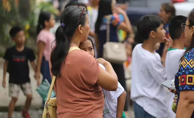 A woman hugs a child as parents and children evacuate a school after a strong earthquake in Davao City, Philippines, on Friday, Oct. 10, 2025. (AP Photo/Manman Dejeto)