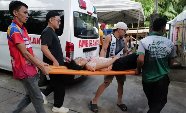 Residents carry a woman on a stretcher at the earthquake-hit Manay town, Davao Oriental province, southern Philippines Saturday, Oct. 11, 2025. (AP Photo/Jeoffrey Maitem)