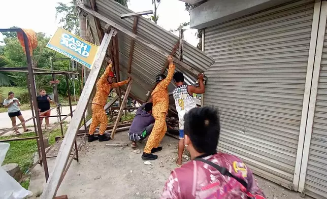 In this photo provided by the Bureau of Fire Protection, firefighters and residents hold on a toppled structure following a strong earthquake in Davao Oriental province, southern Philippines on Friday Oct. 10, 2025. (Bureau of Fire Protection via AP)