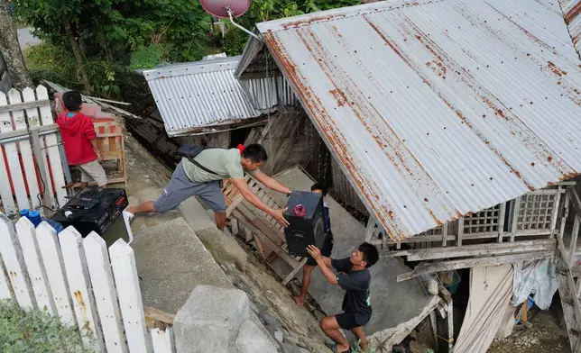 Residents bring out belongings from their earthquake damaged home as they evacuate to safer grounds at Manay town, Davao Oriental province, southern Philippines Saturday, Oct. 11, 2025. (AP Photo/Jeoffrey Maitem)