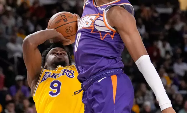 Los Angeles Lakers guard Bronny James, left, shoots as Phoenix Suns forward Ryan Dunn defends during the first half of an NBA preseason basketball game Friday, Oct. 3, 2025, in Palm Desert, Calif. (AP Photo/Mark J. Terrill)