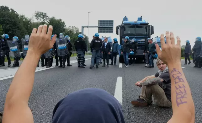 Pro-Palestinian demonstrators sits on the Milan's ring road during a protest part of a national general strike called by different unions to protest against the situation in Gaza two days after Israeli forces intercepted a Gaza-bound aid flotilla in the Mediterranean Sea, in Milan, Italy, Friday, Oct. 3, 2025. (AP Photo/Luca Bruno)