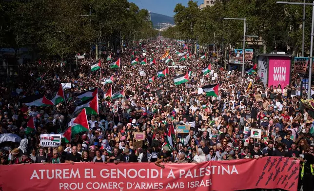 Demonstrators hold a banner with writing reading in Catalan "Let’s stop the genocide in Palestine, no more arms trade with Israel”" during a pro-Palestinian rally in solidarity with the Global Sumud Flotilla after ships were intercepted by the Israeli navy, in Barcelona, Spain, Saturday, Oct. 4, 2025. (AP Photo/Emilio Morenatti)