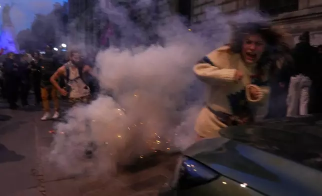 A protester tries to avoid tear gas during a demonstration after a Gaza-bound aid flotilla was intercepted by Israeli Defense Forces in the Mediterranean Sea, Thursday, Oct. 2, 2025 in Paris. (AP Photo/Thibault Camus)