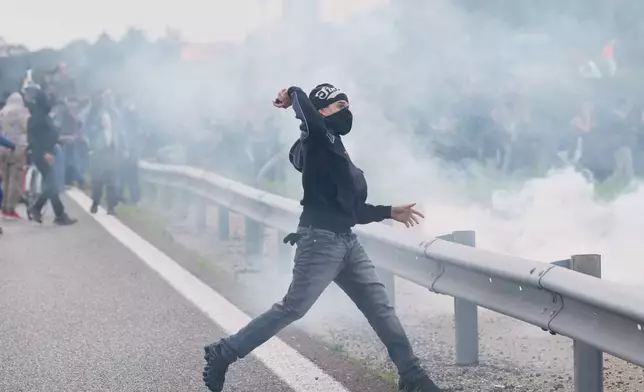 A pro-Palestinian demonstrator throws rocks during a demonstration part of a national general strike called by different unions to protest against the situation in Gaza two days after Israeli forces intercepted a Gaza-bound aid flotilla in the Mediterranean Sea, in Milan, Italy, Friday, Oct. 3, 2025. (AP Photo/Luca Bruno)