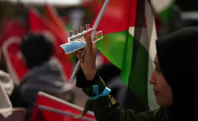 A woman holds a ship glass item during a sit-in gathering against the interception of the Gaza-bound Sumud flotilla by Israeli navy forces, in Istanbul, Thursday, Oct. 2, 2025. (AP Photo/Francisco Seco)