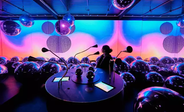 A woman explores an interactive art installation for mixing molecules that make up fragrances during the exhibition "The Secret Power of Scents", showing the history of scent from antiquity to the present as a sensory experience at the Kunstpalast art museum in Duesseldorf, Germany, Tuesday, Oct. 28, 2025. (AP Photo/Martin Meissner)