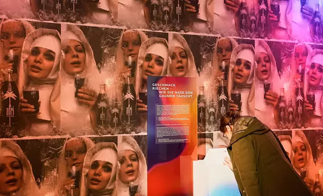 A woman smells samples of Afri-Cola, a popular German soft drink of the 60s and 70s during the exhibition "The Secret Power of Scents", showing the history of scent from antiquity to the present as a sensory experience at the Kunstpalast art museum in Duesseldorf, Germany, Tuesday, Oct. 28, 2025. (AP Photo/Martin Meissner)
