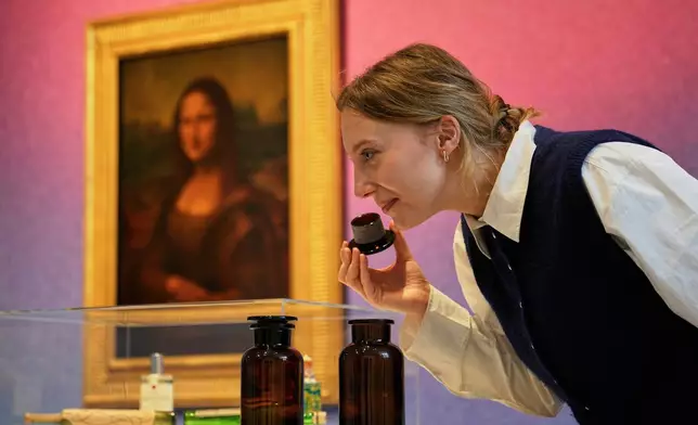 A woman smells samples during the exhibition "The Secret Power of Scents", showing the history of scent from antiquity to the present as a sensory experience at the Kunstpalast art museum in Duesseldorf, Germany, Tuesday, Oct. 28, 2025. (AP Photo/Martin Meissner)