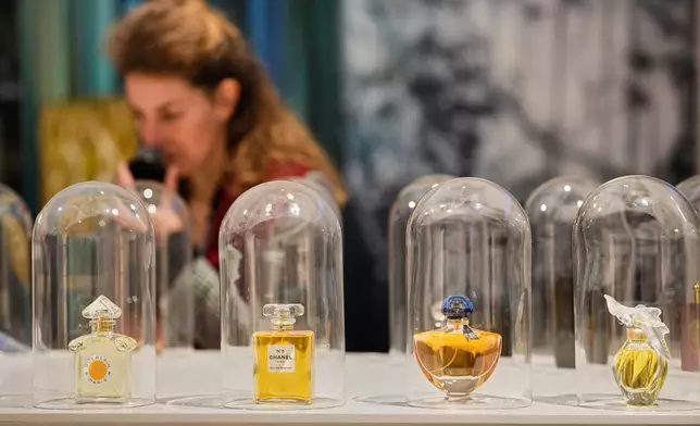A woman smells samples of famous perfumes during the exhibition "The Secret Power of Scents", showing the history of scent from antiquity to the present as a sensory experience at the Kunstpalast art museum in Duesseldorf, Germany, Tuesday, Oct. 28, 2025. (AP Photo/Martin Meissner)
