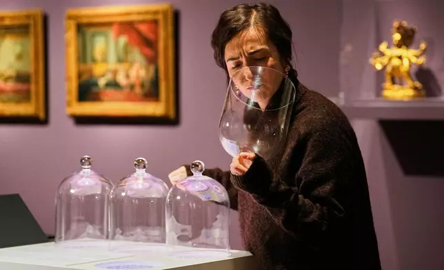 A woman smells samples during the exhibition "The Secret Power of Scents", showing the history of scent from antiquity to the present as a sensory experience at the Kunstpalast art museum in Duesseldorf, Germany, Tuesday, Oct. 28, 2025. (AP Photo/Martin Meissner)