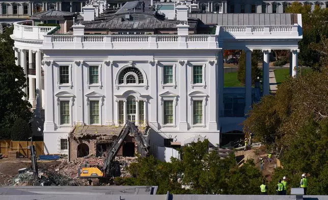 Construction workers atop the U.S. Treasury, bottom right, watch as work continues on a largely demolished part of the East Wing of the White House, Thursday, Oct. 23, 2025, in Washington, before construction of a new ballroom. (AP Photo/Jacquelyn Martin)