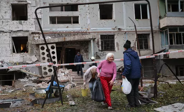 Residents take their belongings from their house destroyed by a Russian strike in Zaporizhzhia, Ukraine, Sunday, Oct. 5, 2025. (AP Photo/Kateryna Klochko)