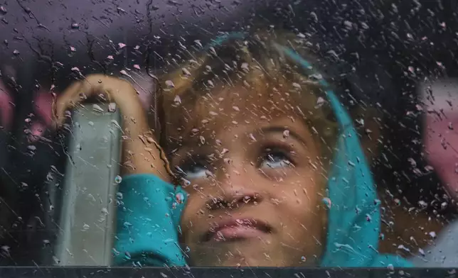 A girl looks out a rain-splattered bus window as she is evacuated before the arrival of Hurricane Melissa in Canizo, a community in Santiago de Cuba, Tuesday, Oct. 28, 2025. (AP Photo/Ramón Espinosa)