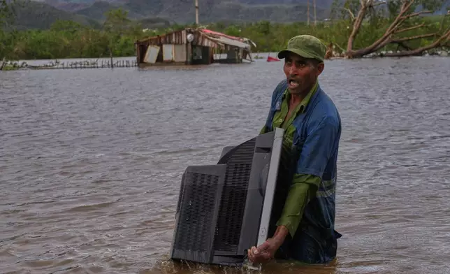 A man carries a TV from his home flooded by Hurricane Melissa in Santiago de Cuba, Wednesday, Oct. 29, 2025. (AP Photo/Ramon Espinosa)